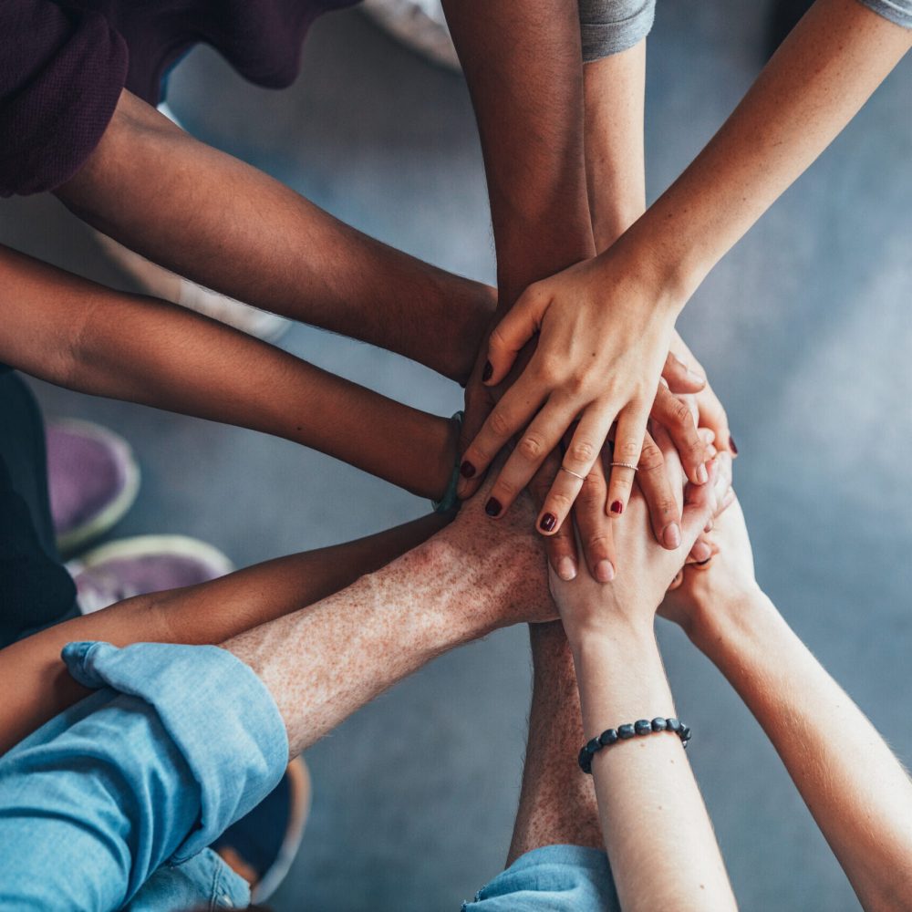 Close up top view of young people putting their hands together. Friends with stack of hands showing unity and teamwork.